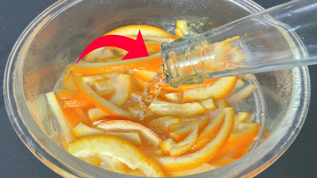 Chai thủy tinh đang rót chất lỏng vào tô chứa các lát cam, có mũi tên đỏ chỉ hướng rót.