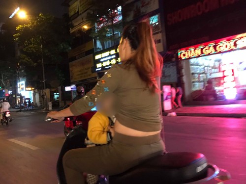 Người mẹ một tay lái xe máy, một tay ôm con bú trên đường. Ảnh H.A.